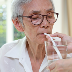 oudere man krijgt water te drinken met een rietje