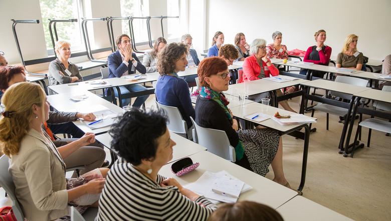 groep mensen zit aan schoolbureau's en luisteren